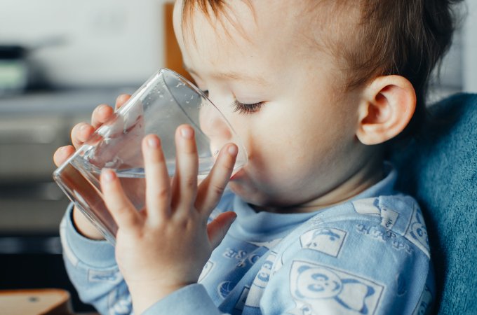 a baby drinking a glass of water