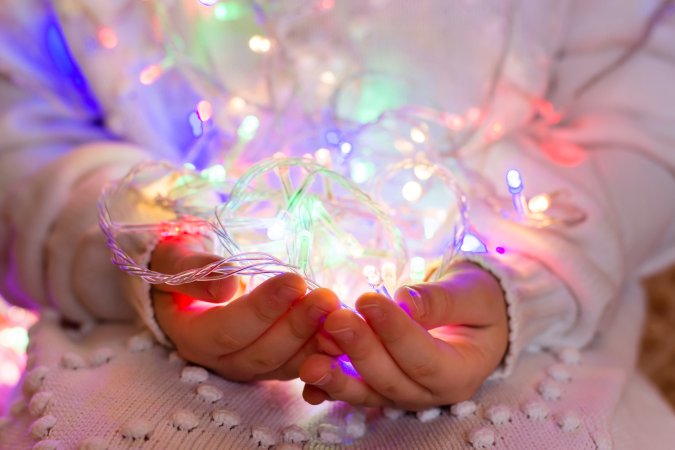 a person holding LED lights in their hands while wearing a white sweater